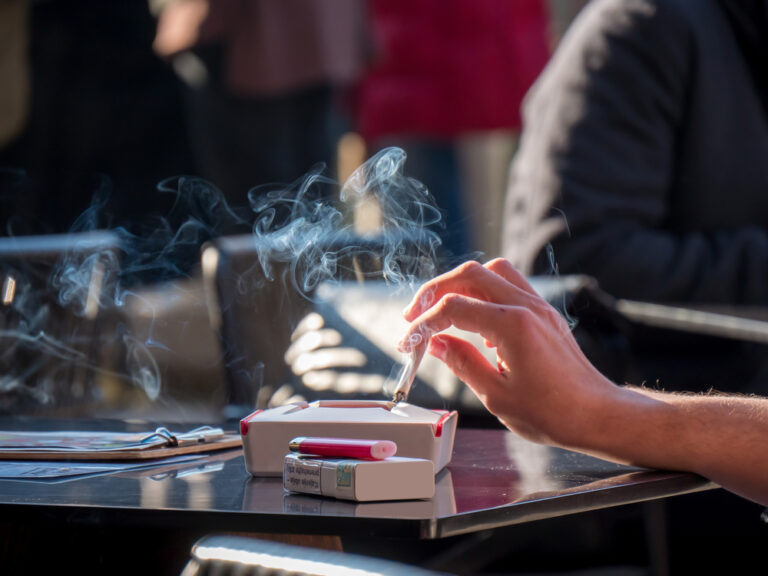 Adult,Woman,Hand,Holding,Smoking,Cigarette,Above,Ashtray,At,Restaurant