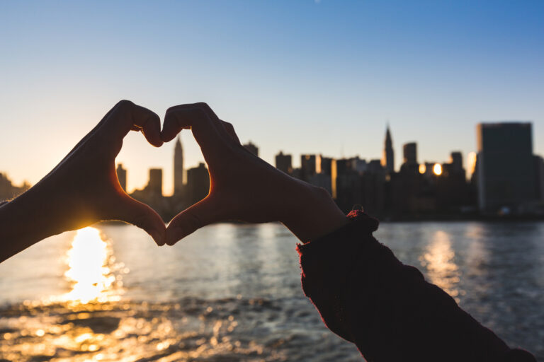 Heart,Shaped,Hands,At,Sunset,,New,York,Skyline,On,Background