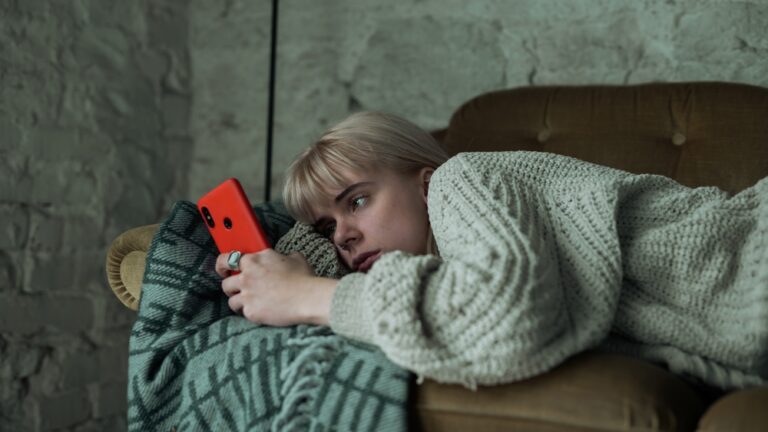 Depressed,Young,Blonde,Woman,Scrolling,Through,Her,Phone,,Refusing,To
