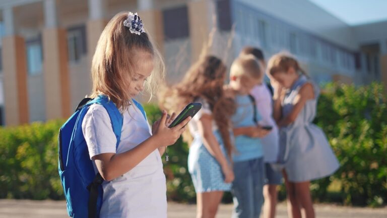 Pupils,Stand,In,The,Schoolyard,And,Look,At,Phones