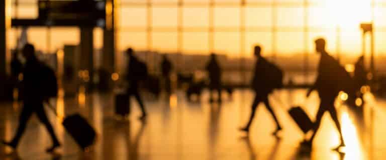 Silhouetted,Figures,With,Luggage,Walking,In,A,Bright,Airport,Terminal